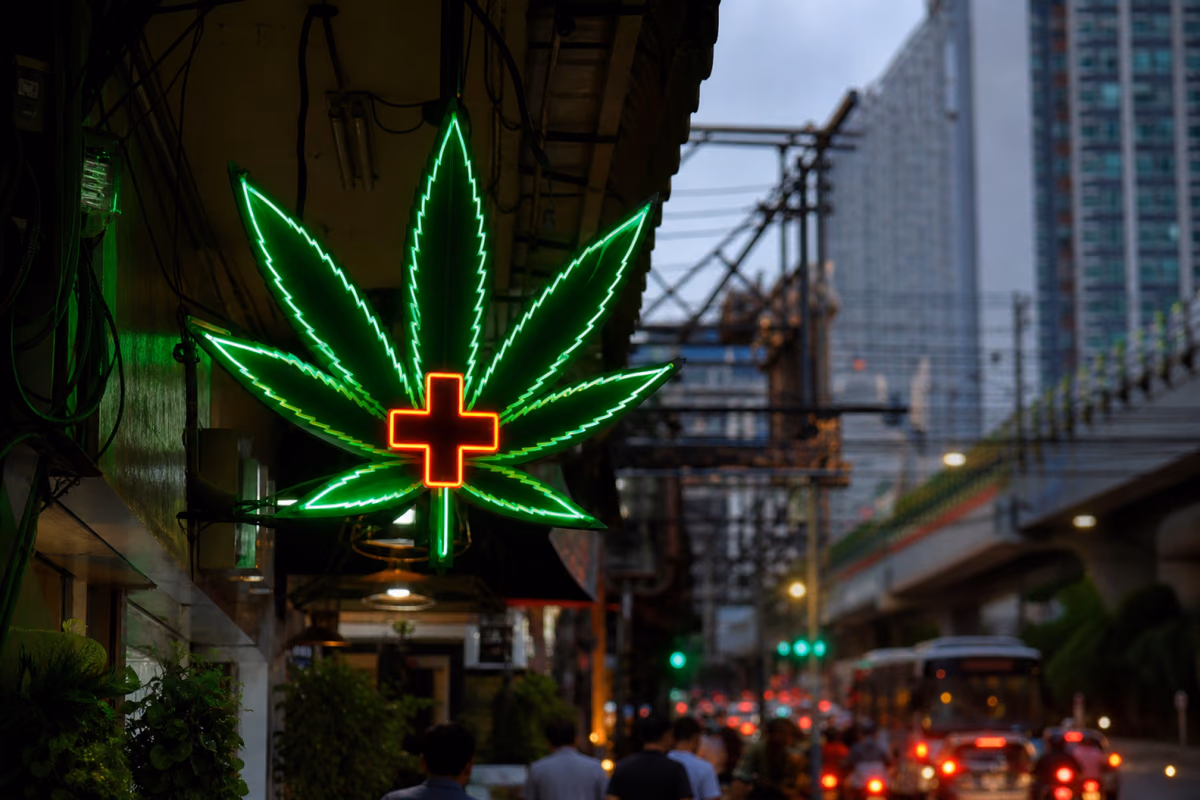 Neonschild in Form eines Cannabisblatts mit medizinischem Kreuz an einer belebten Straße in Bangkok, Thailand